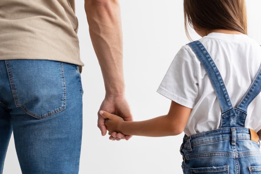 Rear view of a father and daughter holding hands 