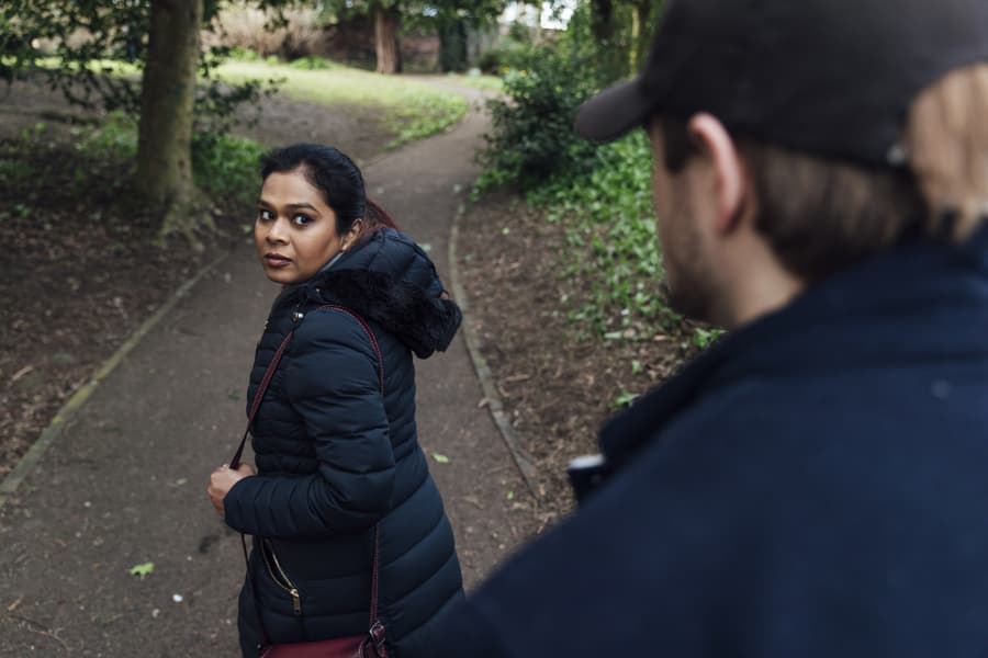 Frightened woman looking over her shoulder at man following her 