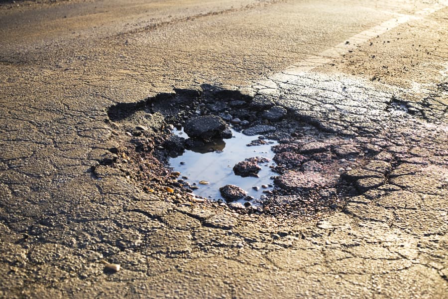 Large pothole filled with water on an asphalt road