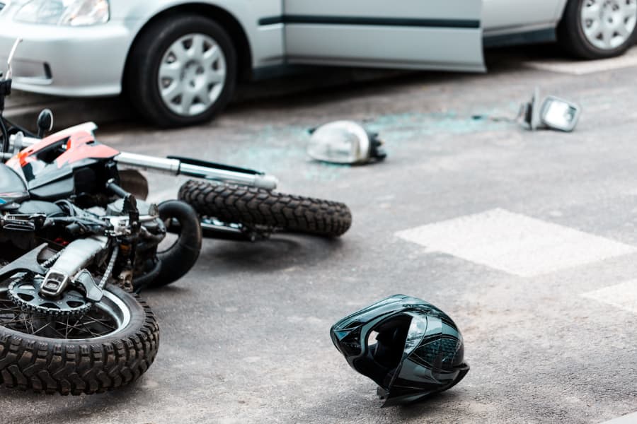 Motorcycle, broken glass, and helmet on the street after collision with a car