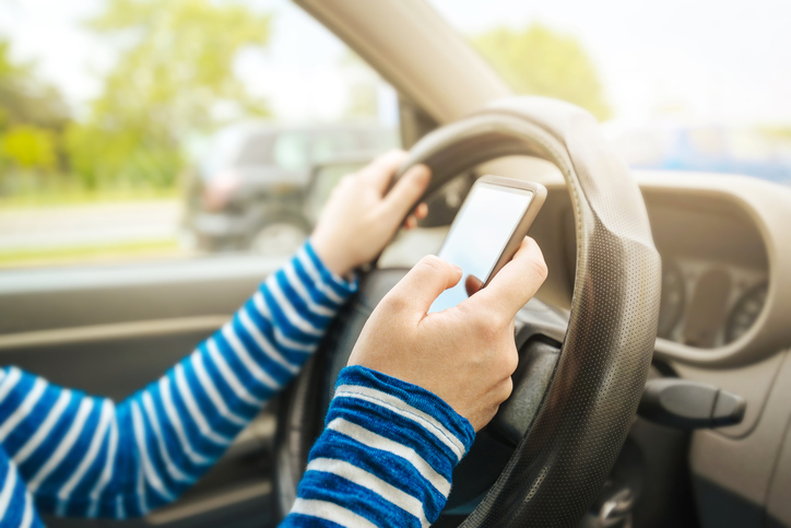 Teen driving car and texting on phone