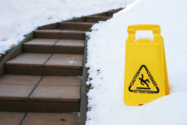 Slippery winter stairs with caution sign