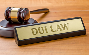 Engraved nameplate that reads DUI near a gavel on a desk