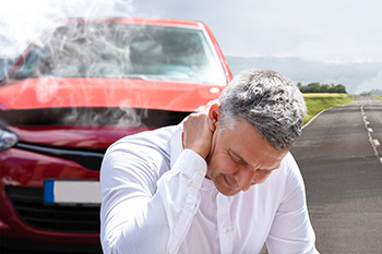 Man holding his neck in pain at car accident scene