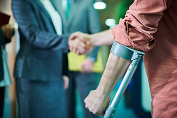 A man using a crutch shaking an accident lawyer’s hand