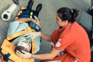 woman emergency technician looking after a man strapped to a stretcher with bandages on his head