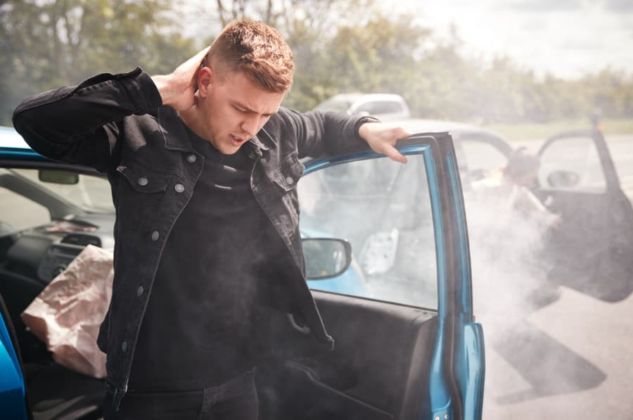 male passenger getting out of car holding his neck after car accident