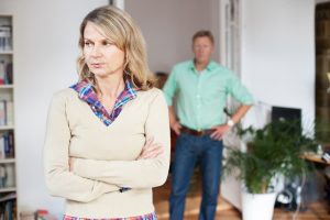 upset older woman standing with older man in the background