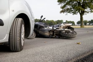 motorcycle laying on road after being hit by car