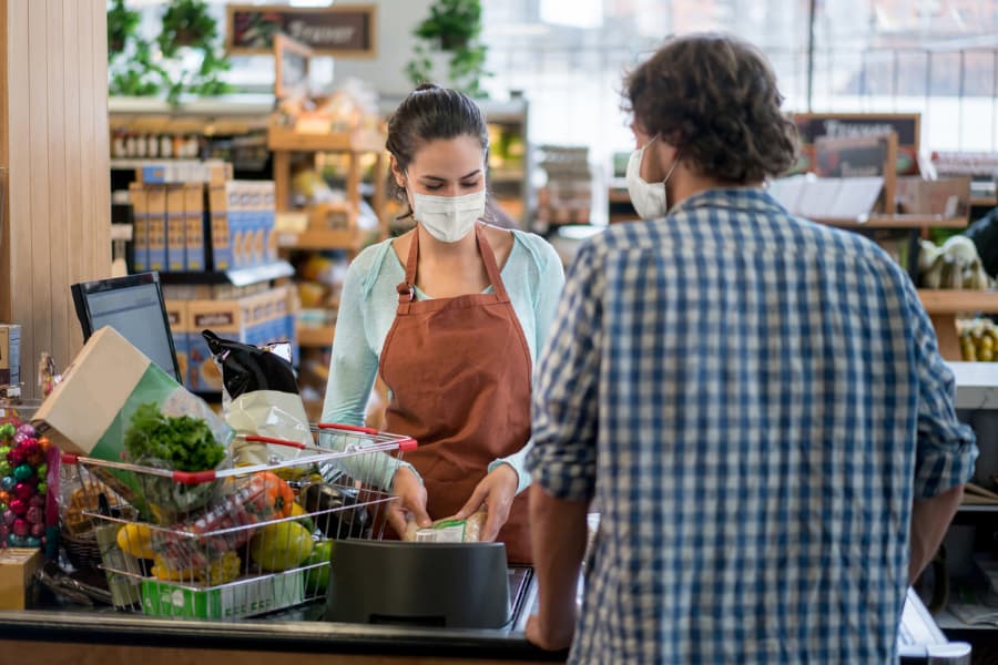 man wearing a protective mask checking out at grocery store 