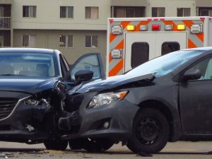 two cars smashed in a collision and an ambulance in the background