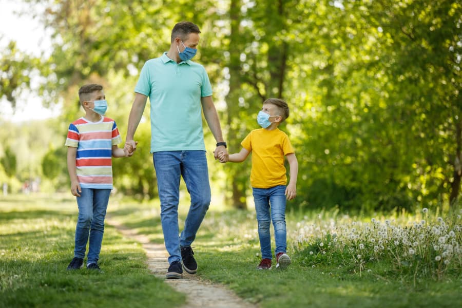 Father with two sons wearing protective masks in a park