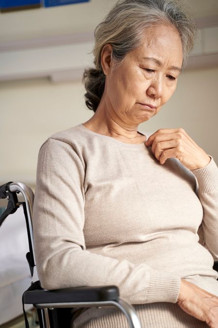sad elderly Asian woman sitting alone in wheelchair