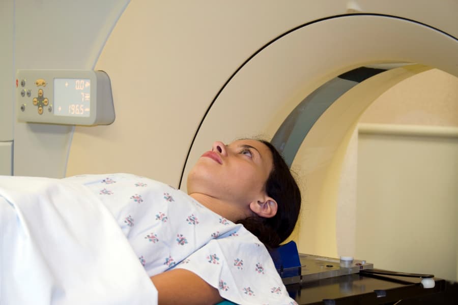 a young woman lying on a table undergoing a CAT scan