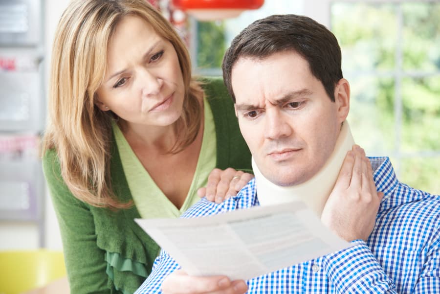 husband in a neck brace looking over a document with wife 