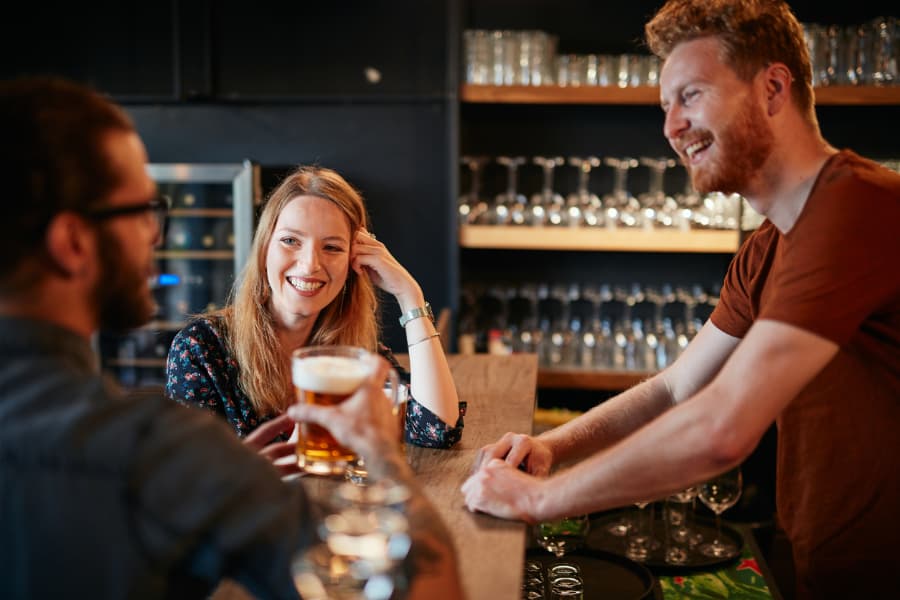 man and woman sitting at a bar talking to the bartender