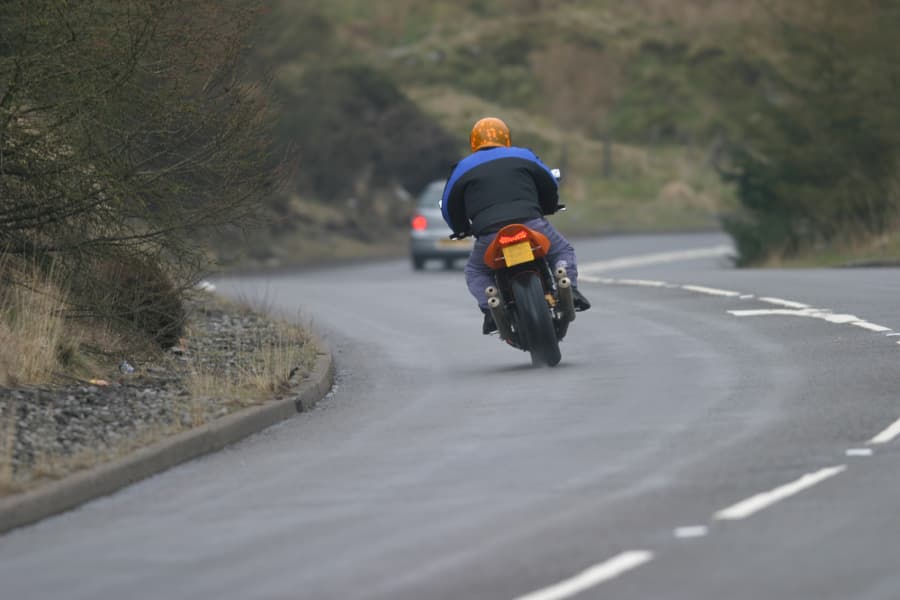 motorcycle rider following car on winding road