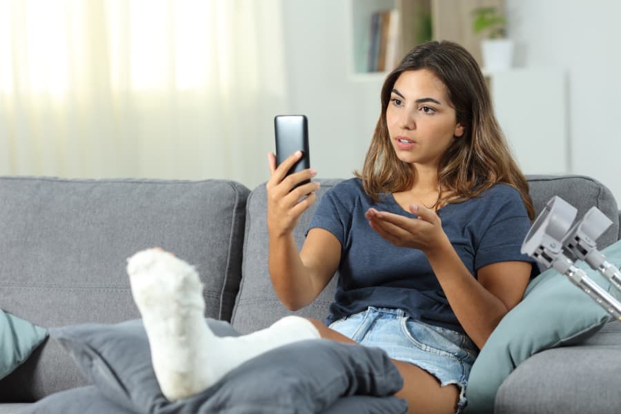 Woman With Cast On Leg Looking At Phone