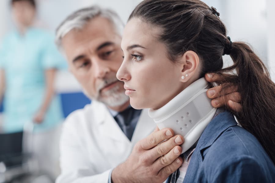 Doctor fitting young woman with neck brace