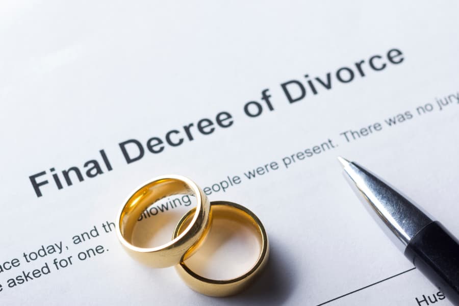 Divorce decree with wedding rings and pen