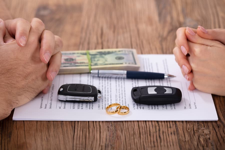 Divorce documents wedding rings money and car keys on table 