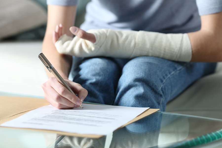 Woman With Injured Arm Signing Personal Injury Settlement Papers