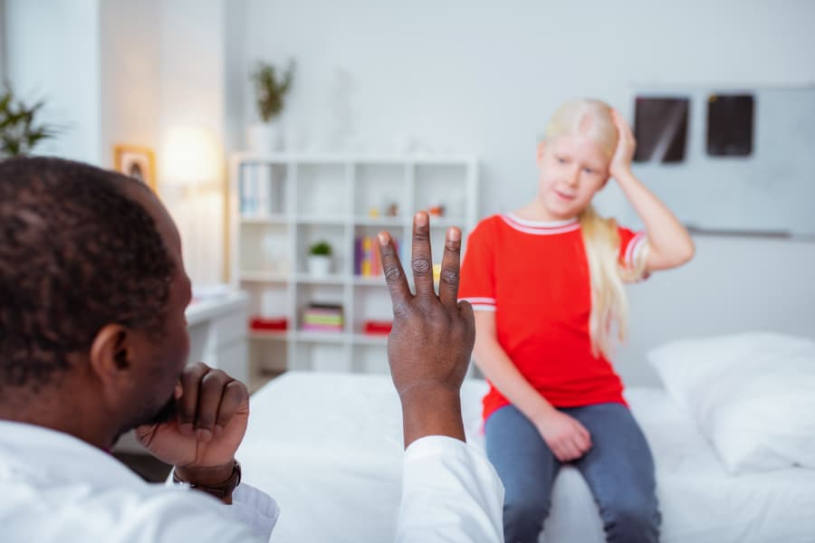 Doctor Holding Up Three Fingers While Testing A Girl With Head Injury