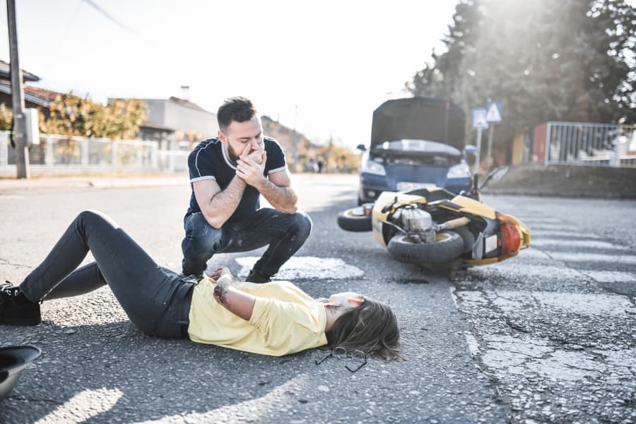Man crouching down to help a woman after a motorcycle accident