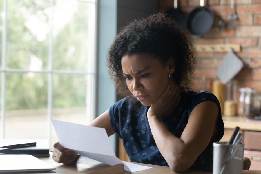 Perplexed woman sitting at laptop reading a medical bill