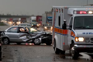 Auto accident scene on a rainy highway with an ambulance in the foreground