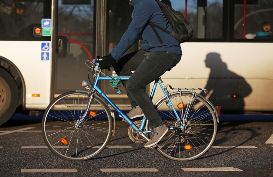 Bicyclist riding a blue bike next to a city bus