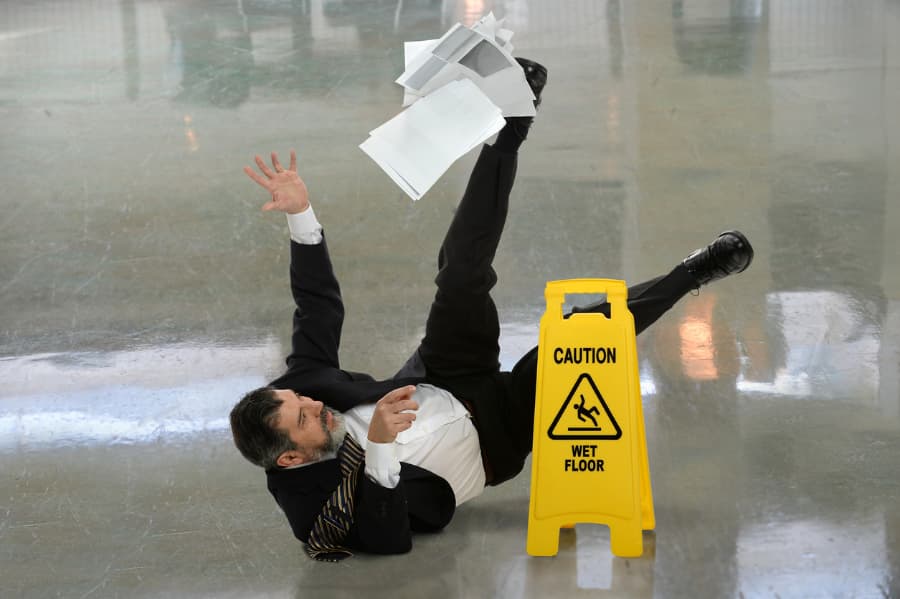 Man falling near wet floor sign