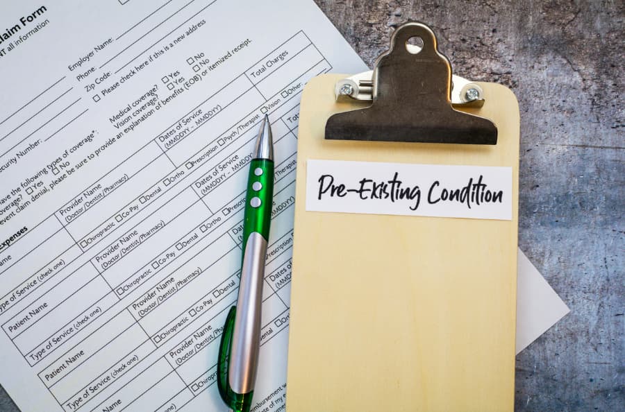 Claim form with a pen and clipboard that says “pre-existing condition”