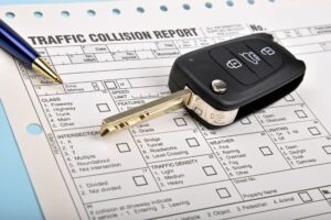 Close-up of a traffic collision report with pen and car key on top