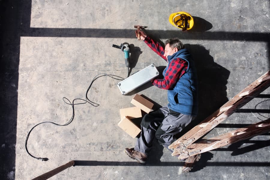 Construction worker lying on the ground after a fall off a ladder