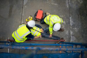Workers assisting a construction worker who has fallen from a scaffold