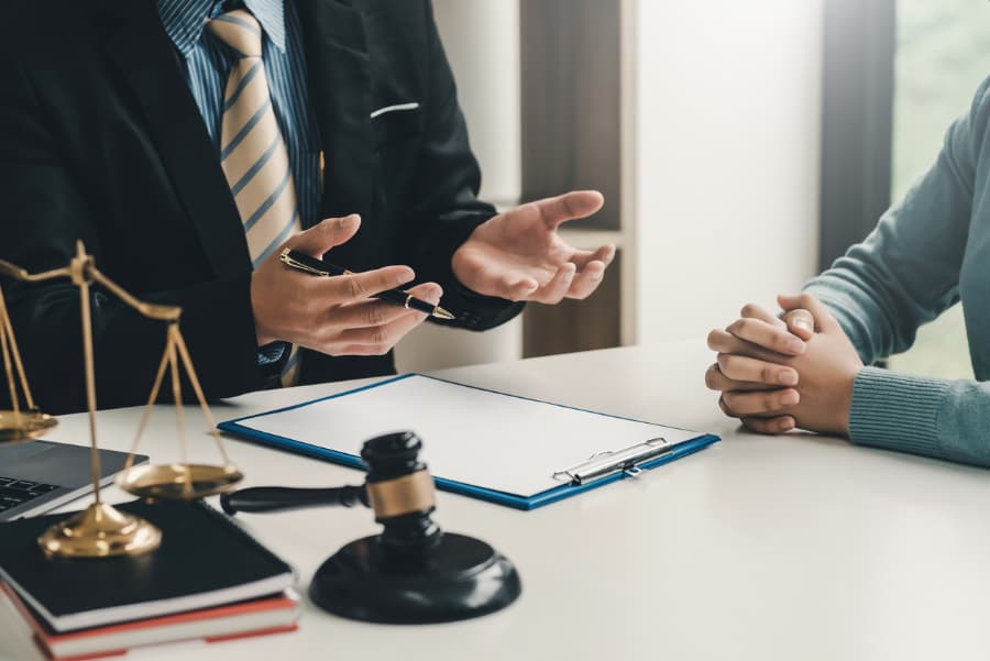 lawyer sitting at a desk explaining a case to a woman with a gavel and scales in the foreground