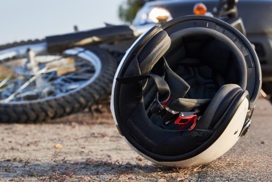 Close-up of a wrecked motorcycle and helmed with a car in the background