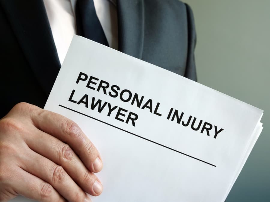 A close-up of a man in a dark suit holding a paper that says personal injury lawyer 