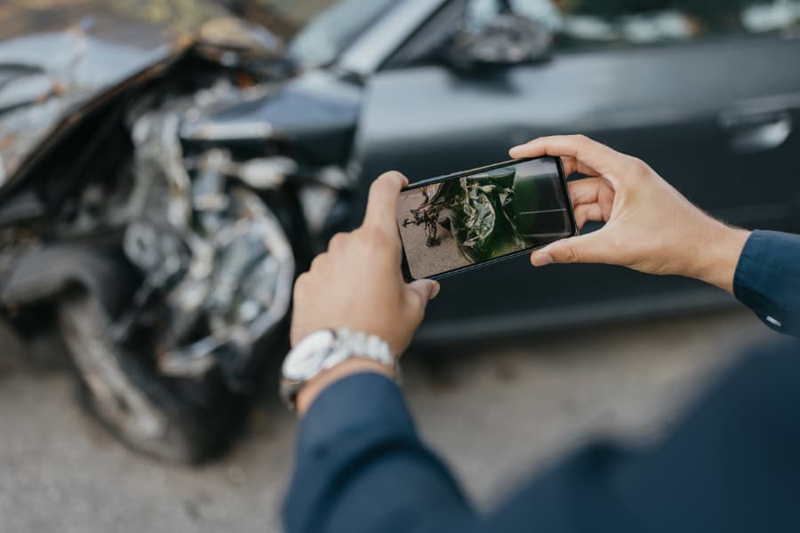 Close-up of a man taking photos of a damaged car after crash